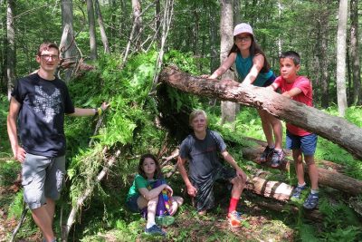 4-H campers with a fort they built in the woods