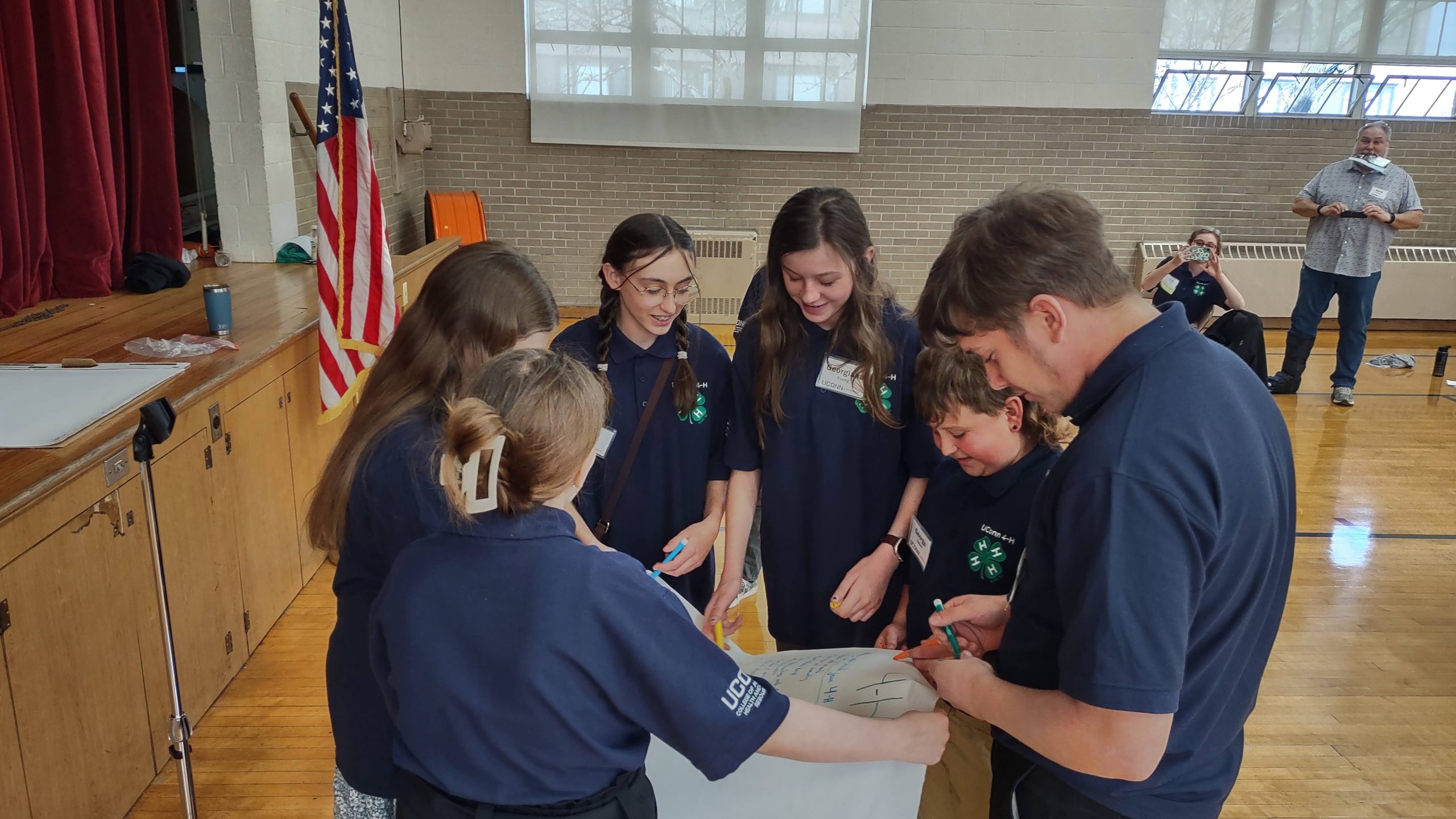 Youth in blue polos standing around a poster board 
