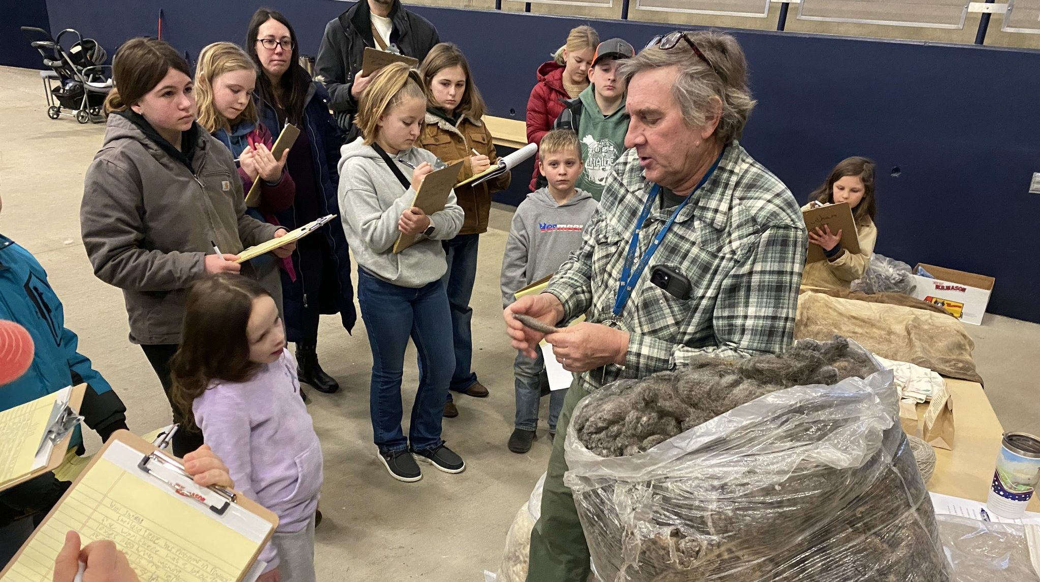 Man holding wool with students taking notes and listening to presentation 