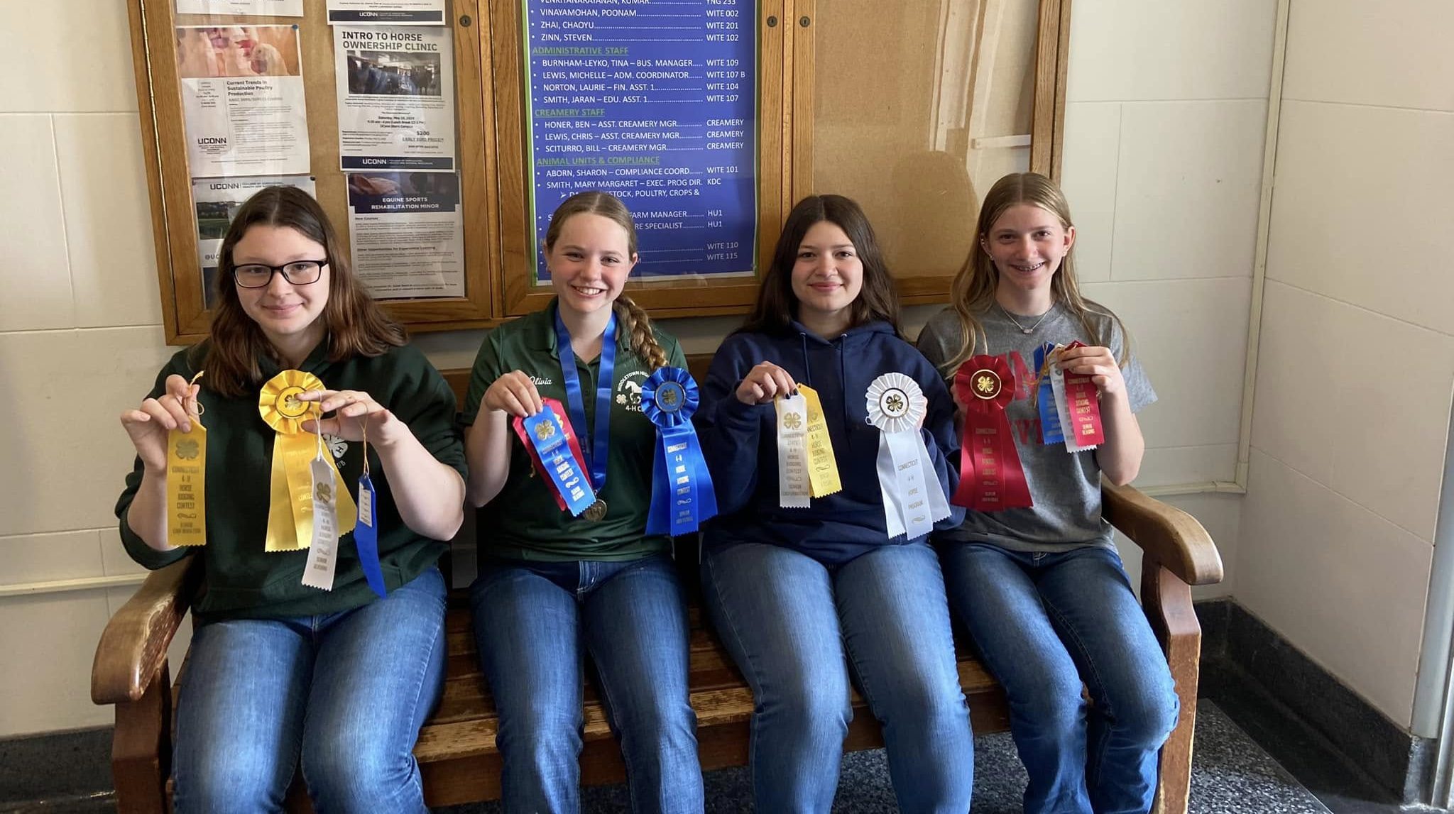 Four students holding ribbons sitting on a bench