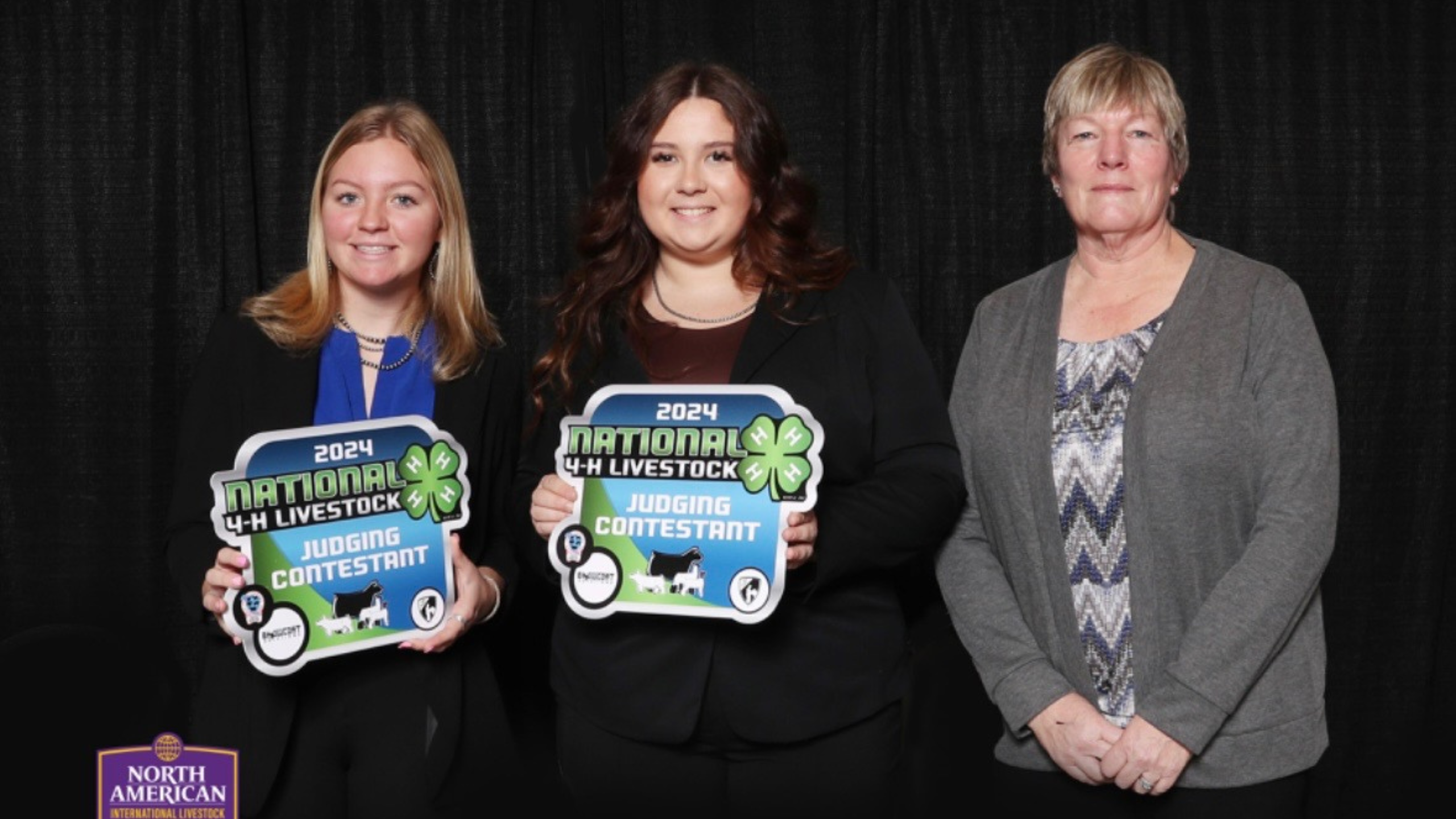 2 youth and one adult holding judging contest boards behind a black background