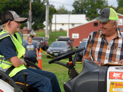 Youth and club leader smiling on tractors