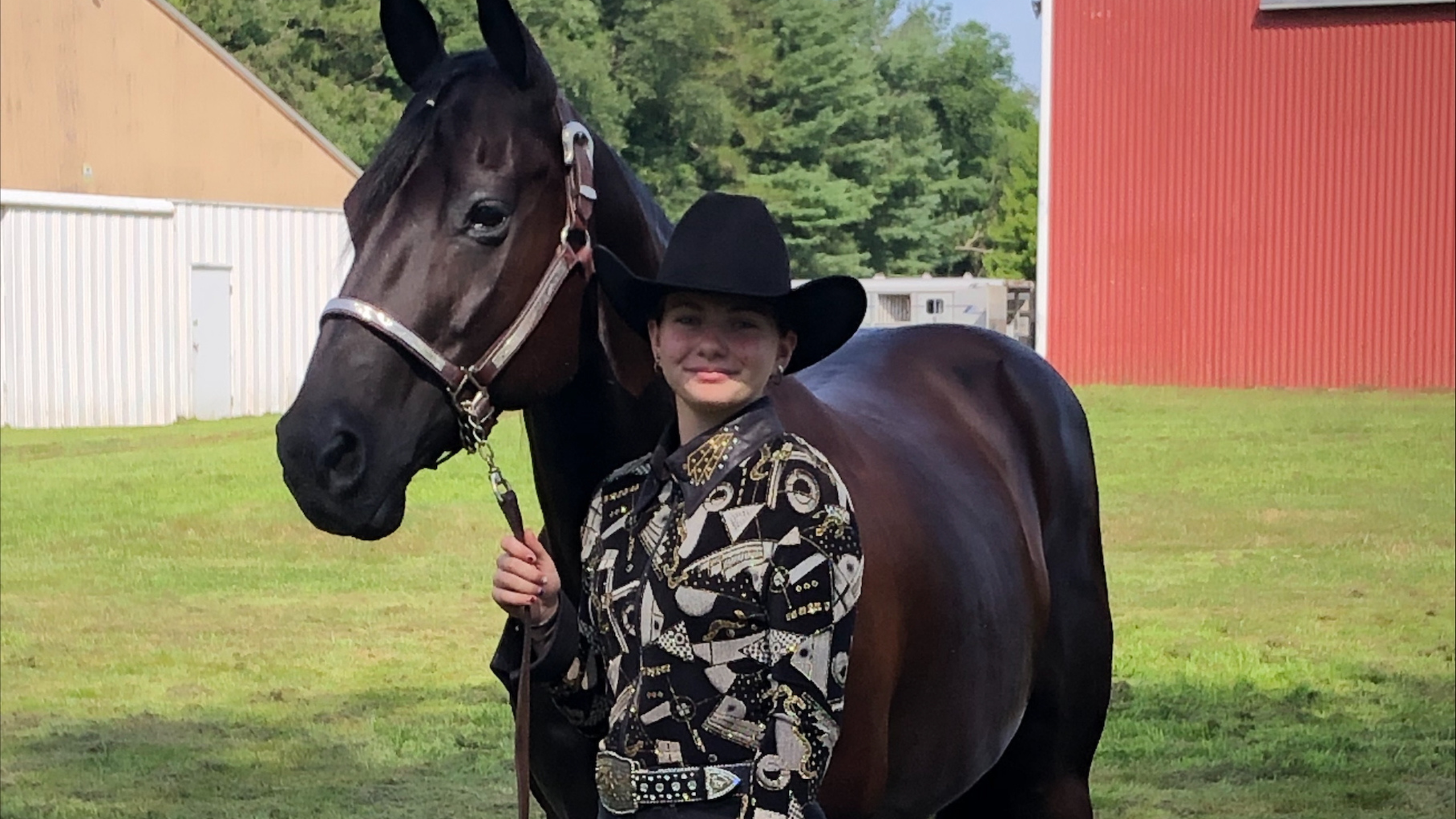 Girl wearing western attire with a black horse