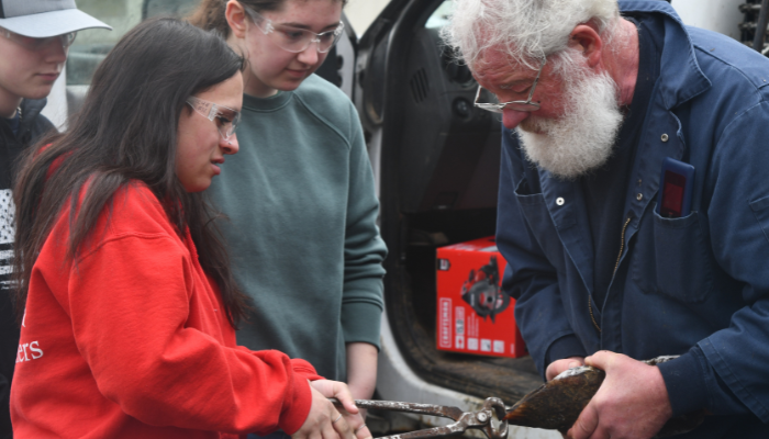 Youth using tool on model hoof